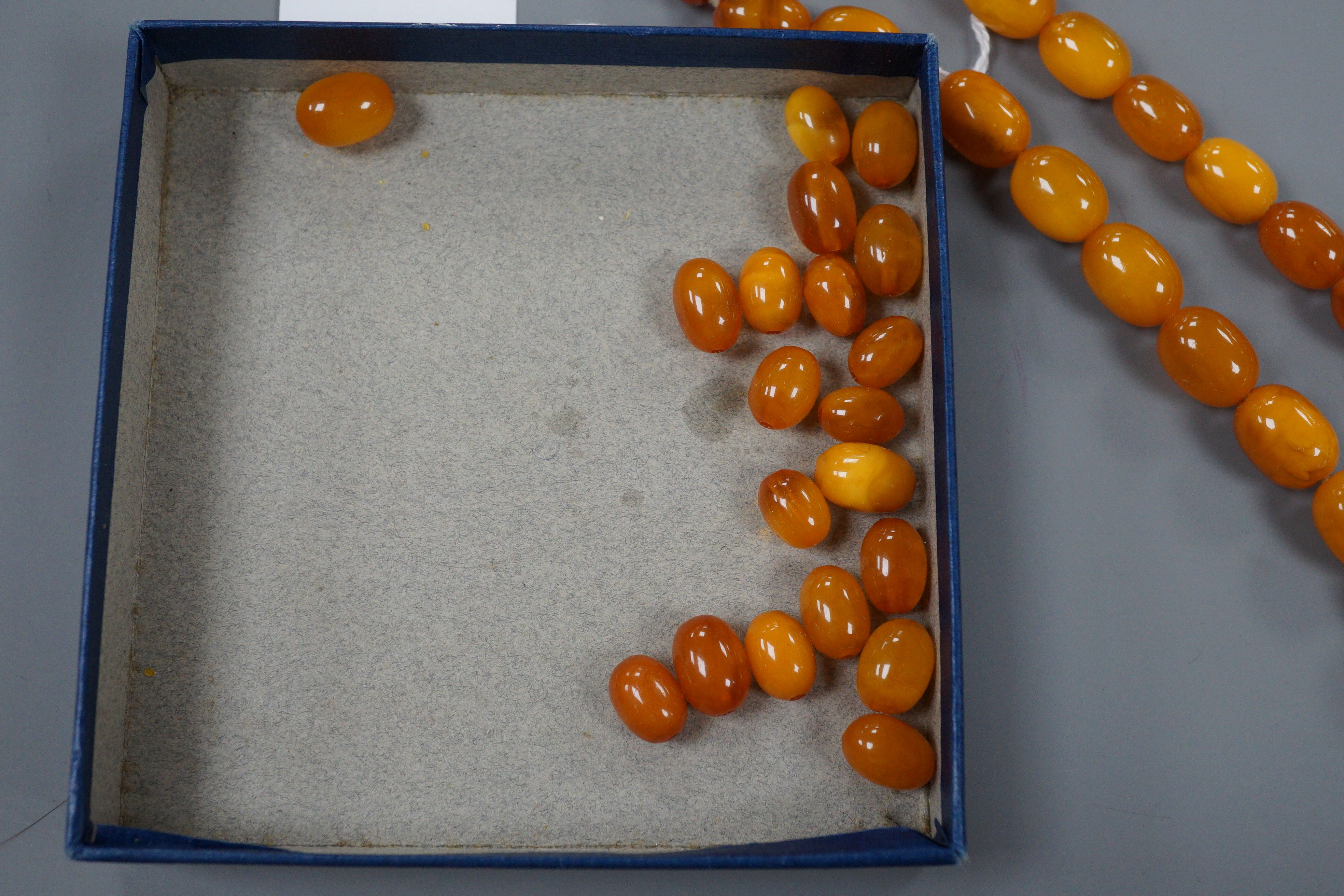 A single strand graduated oval amber bead necklace, 42cm, gross 49 grams and assorted loose amber beads, 15 grams.